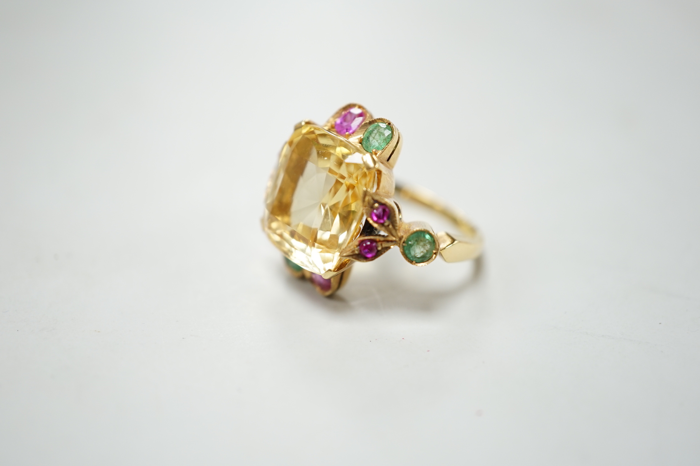 An 18ct and single stone yellow sapphire set dress ring, with emerald and ruby set setting and shoulders, size M, gross weight 9.4 grams.